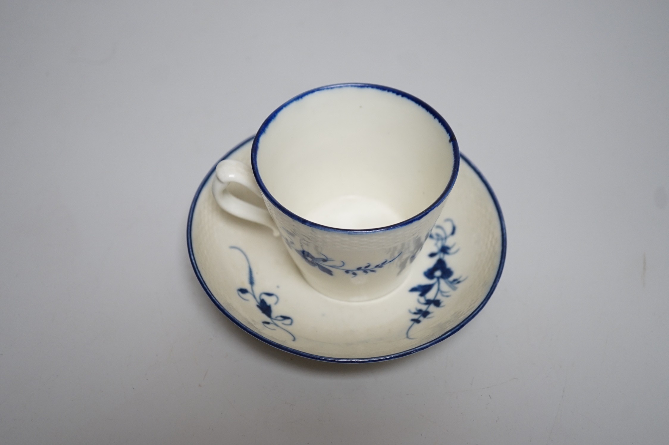 An 18th century Caughley coffee cup and saucer, Chantilly sprigs under a basket weave moulded border, saucer 13cms diameter